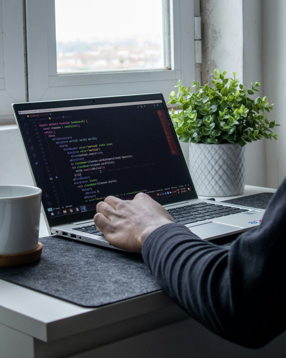 Laptop with code on a desk beside a window